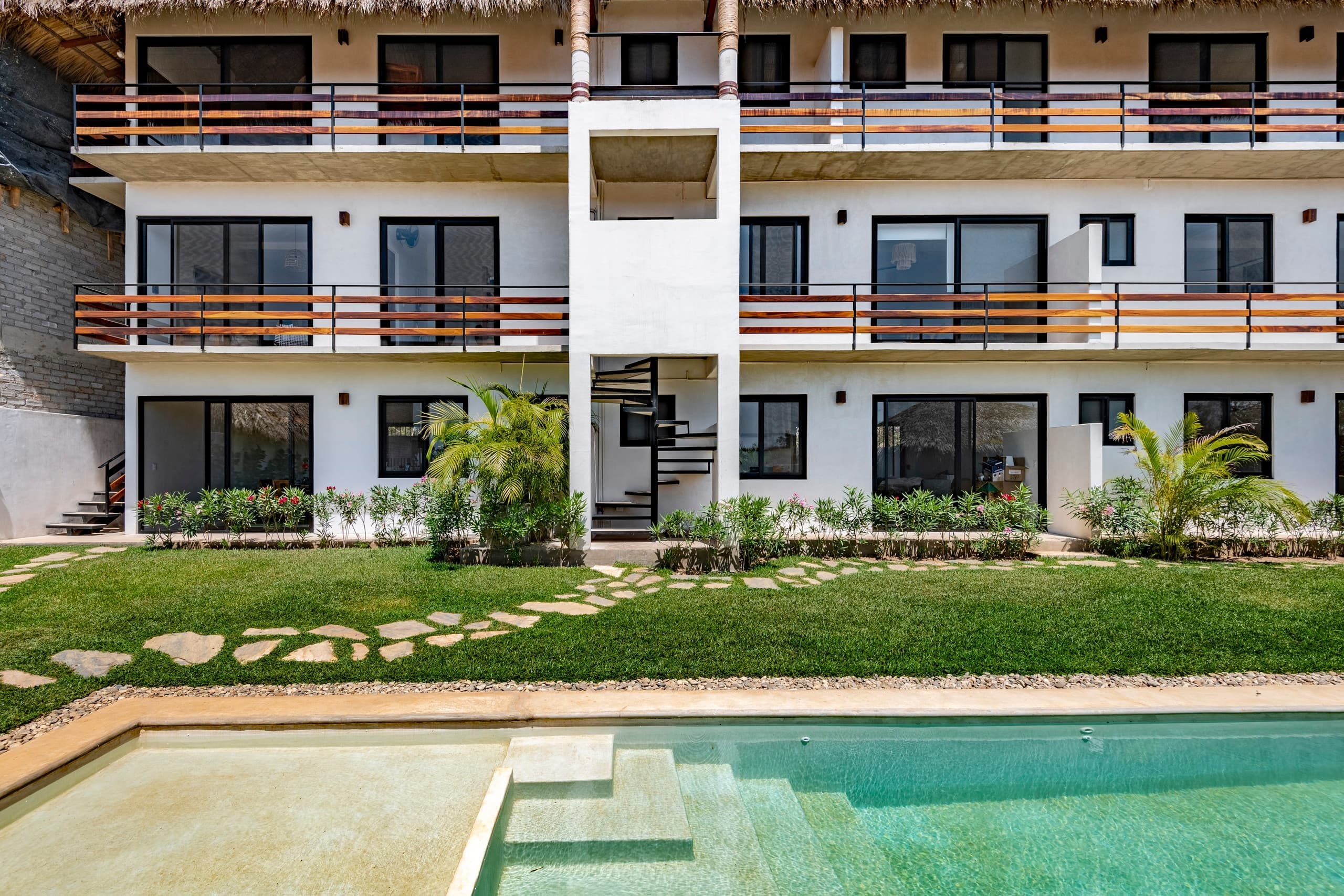 Fachada de La Cruz Condos con alberca y jardín