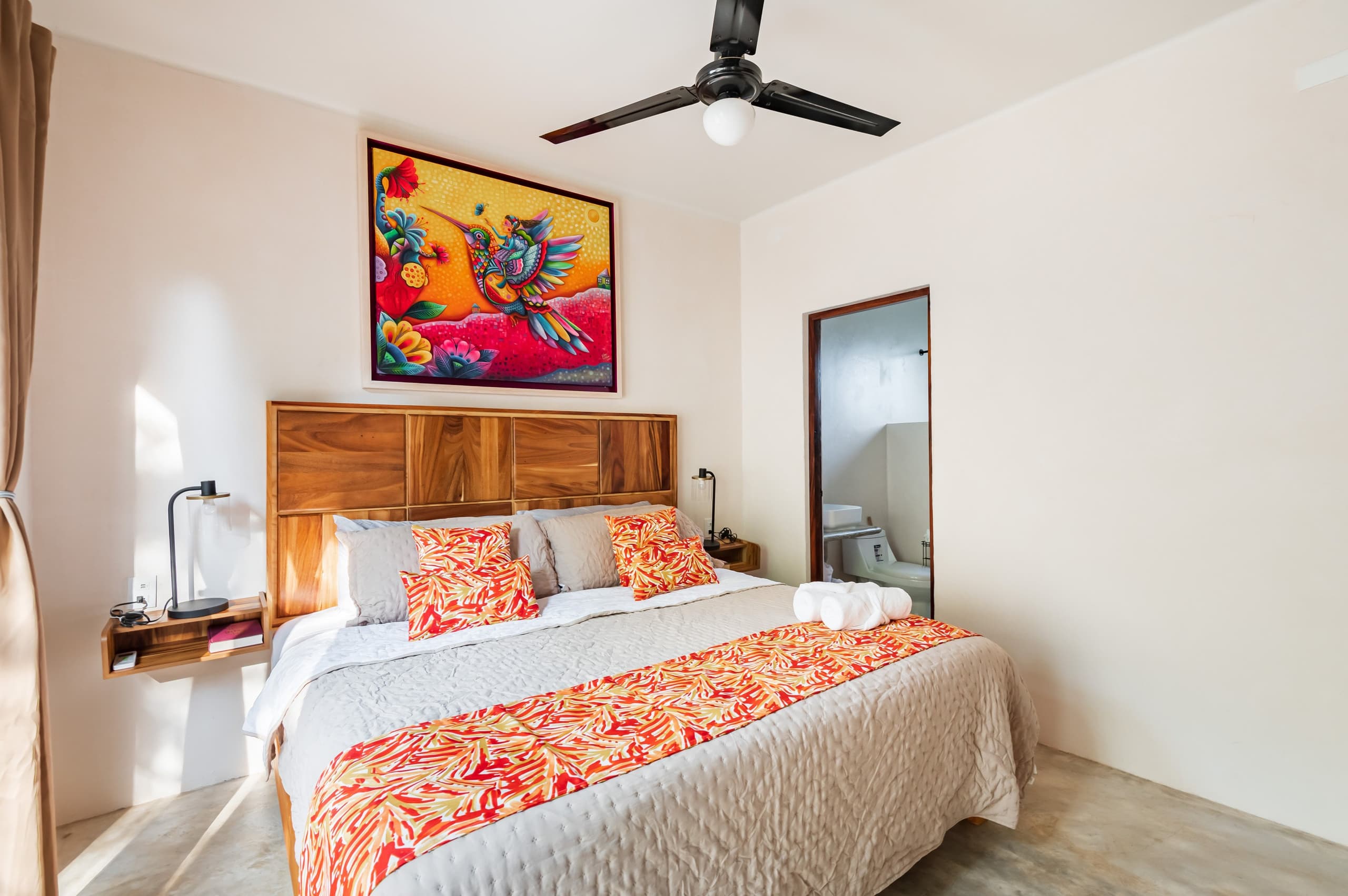 Cama king con buró de madera y acceso al baño